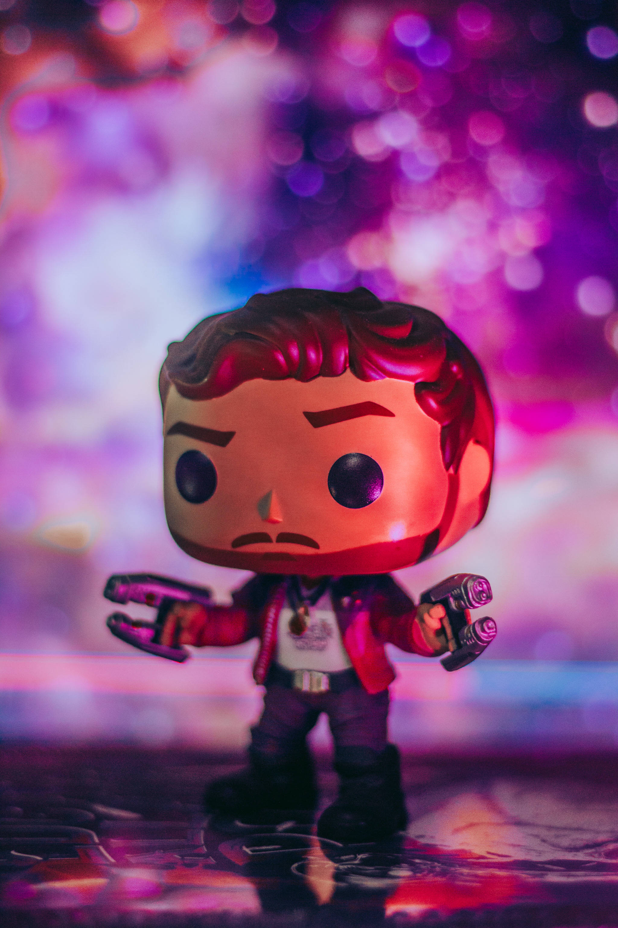 Funko Pop 彼得·奎爾 壁紙 — 星爵的Funko Pop公仔站在充滿活力的紫色和粉紅色散景背景上，下方有反射表面。