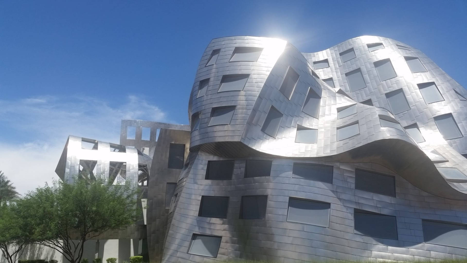 未來風格的銀色建築，在明亮藍天下帶有波浪形面板