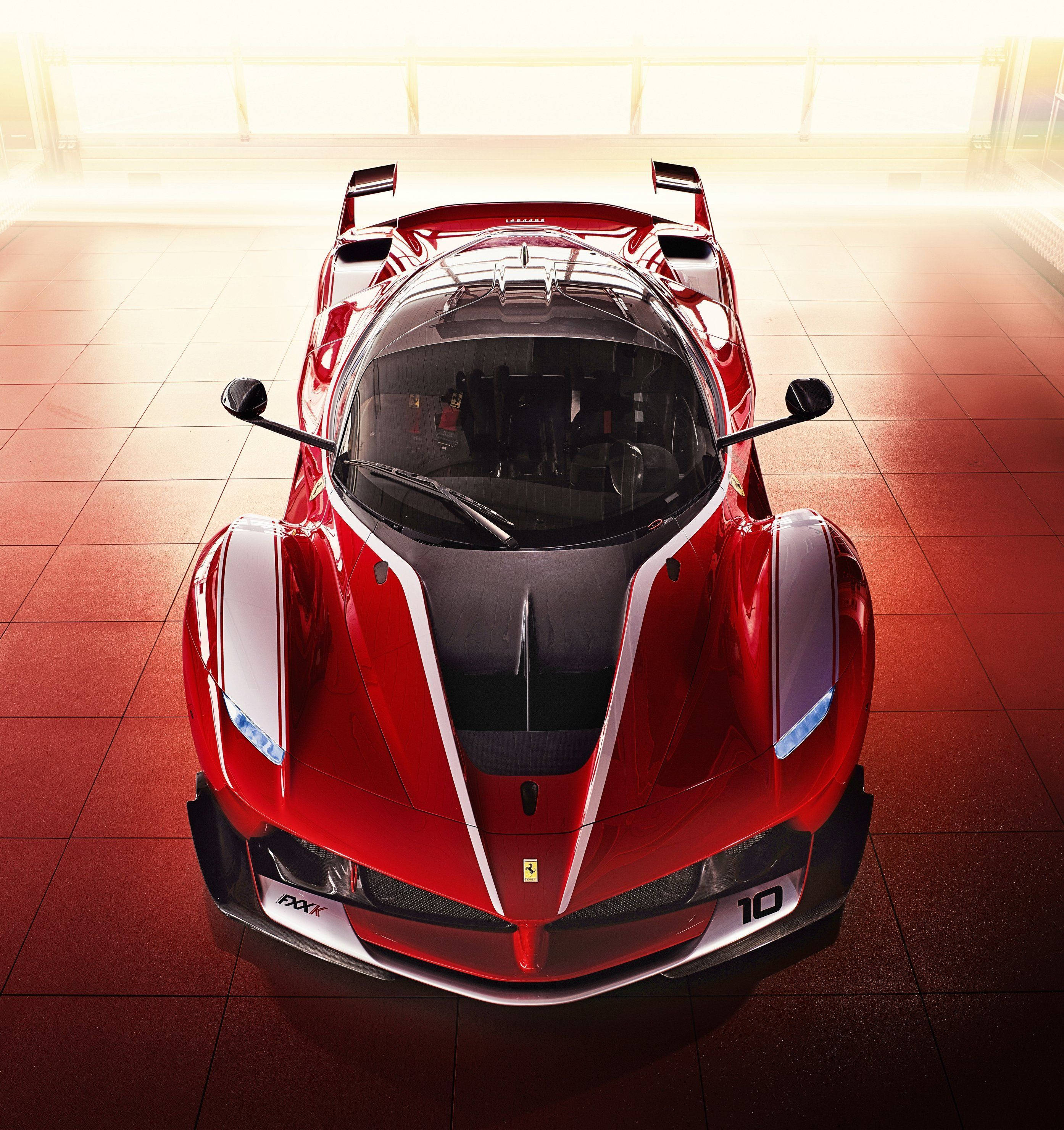 FXX-K法拉利手機頂視圖壁紙 壁紙 — 從上方俯瞰一輛光澤紅色法拉利SF90 Stradale超級跑車，停在舖有瓷磚地板的陽光車庫中。