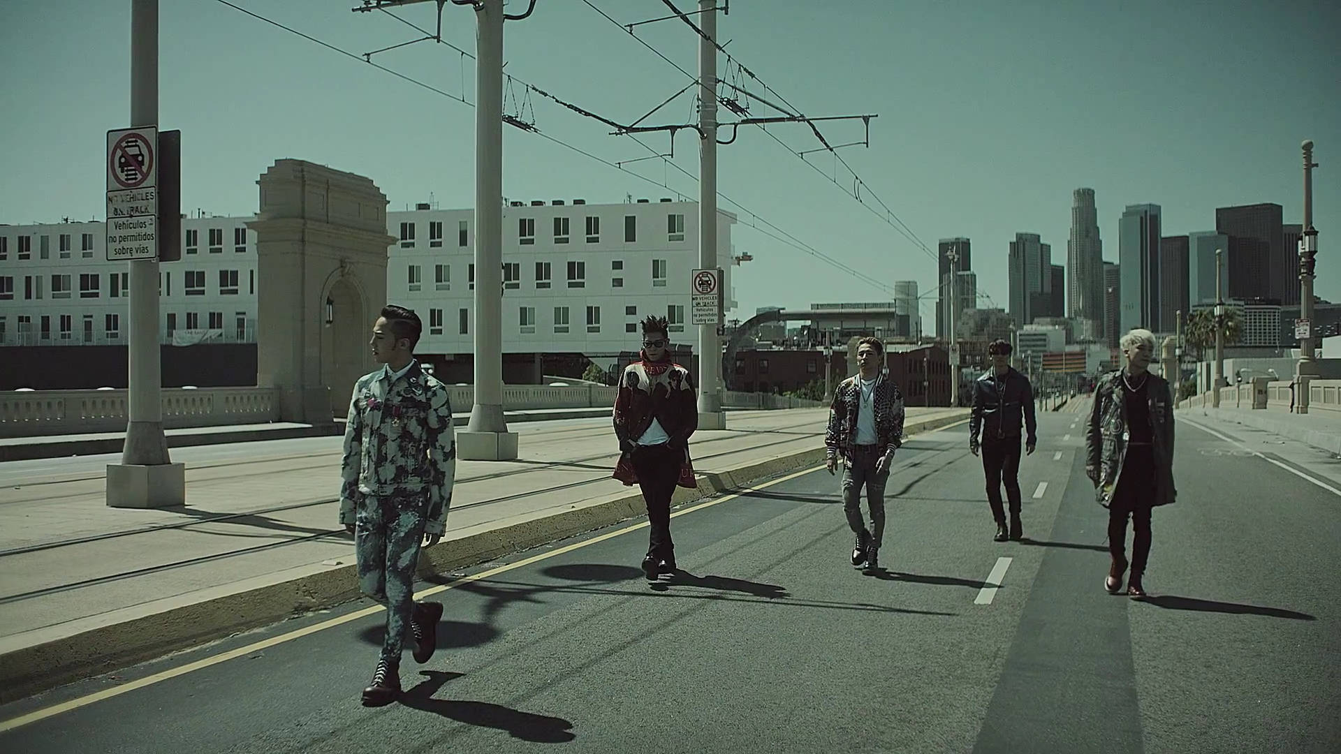 G-Dragon《Loser》MV 精彩畫面 壁紙 — 五位穿著時尚的男士自信地走過陽光明媚的城市橋樑，背景是城市天際線。