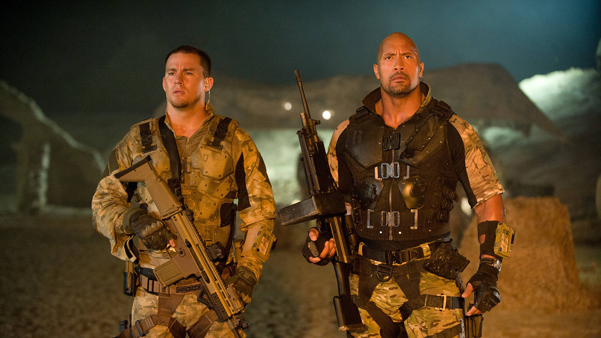 G.I. Joe精銳小隊雙人組 壁紙 — 兩名身穿戰術裝備的士兵在夜間於沙漠戰場上，在昏暗的人造燈光下保持警覺。