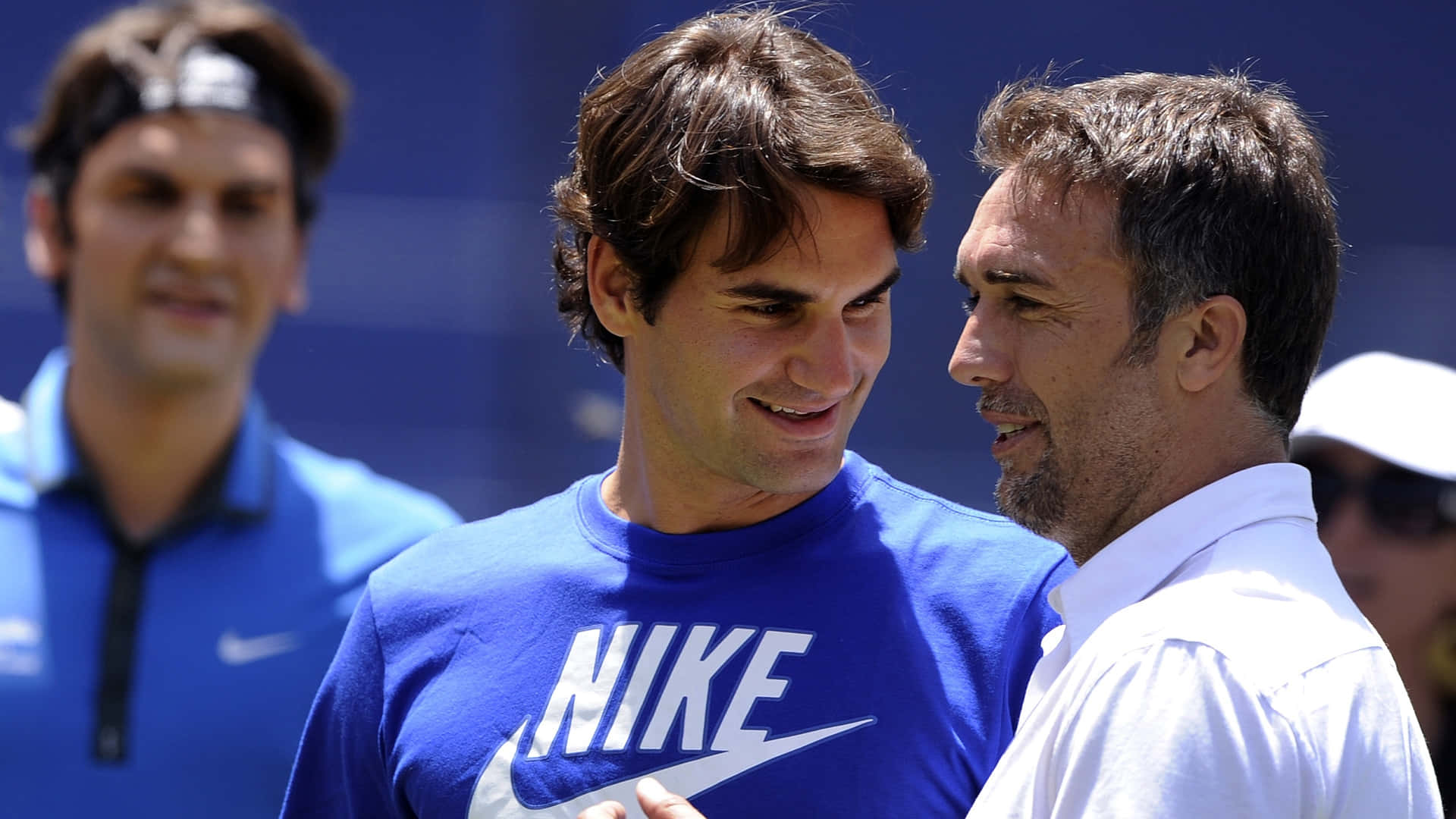 Gabriel Batistuta 與 Roger Federer 壁紙 — 羅傑·費達拿在明亮的日光下與一名身穿白衫的男子親切交談，面露溫暖笑容。