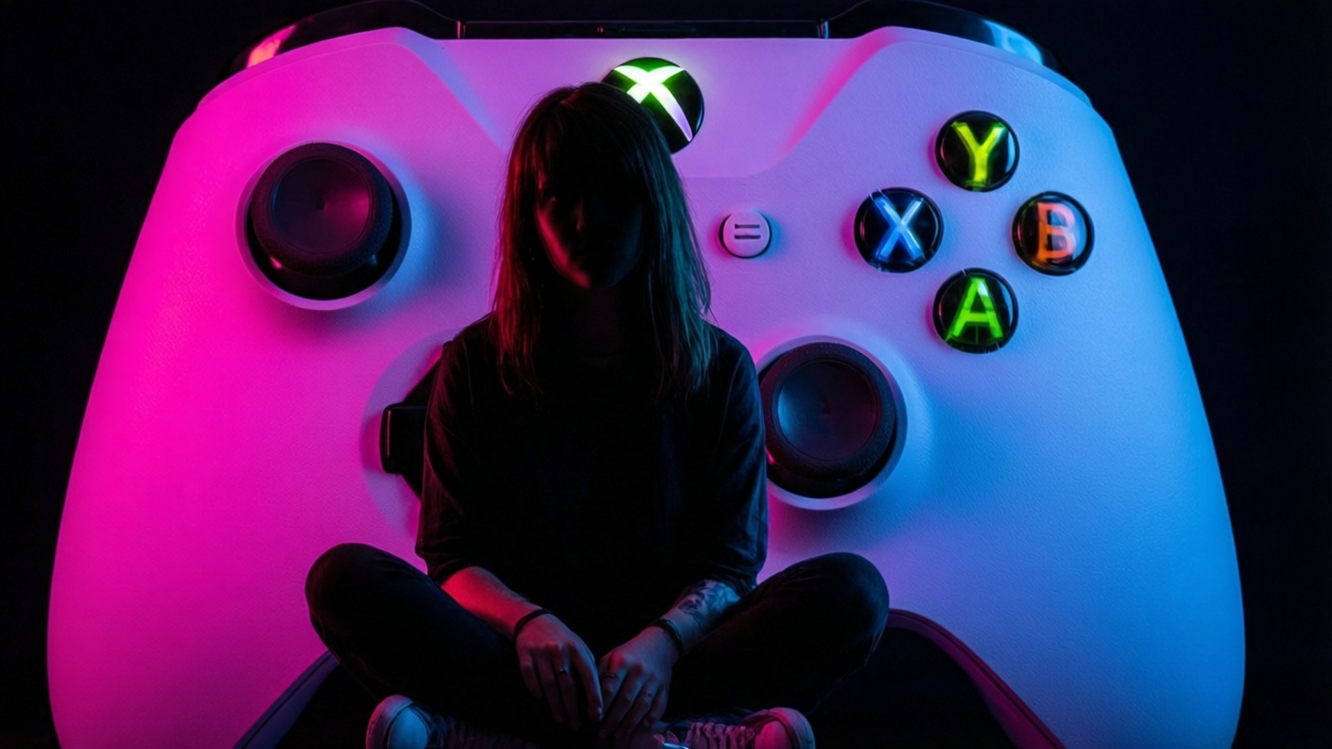 人坐在一個巨大的發光Xbox控制器內，帶有霓虹粉紅色和藍色燈光。