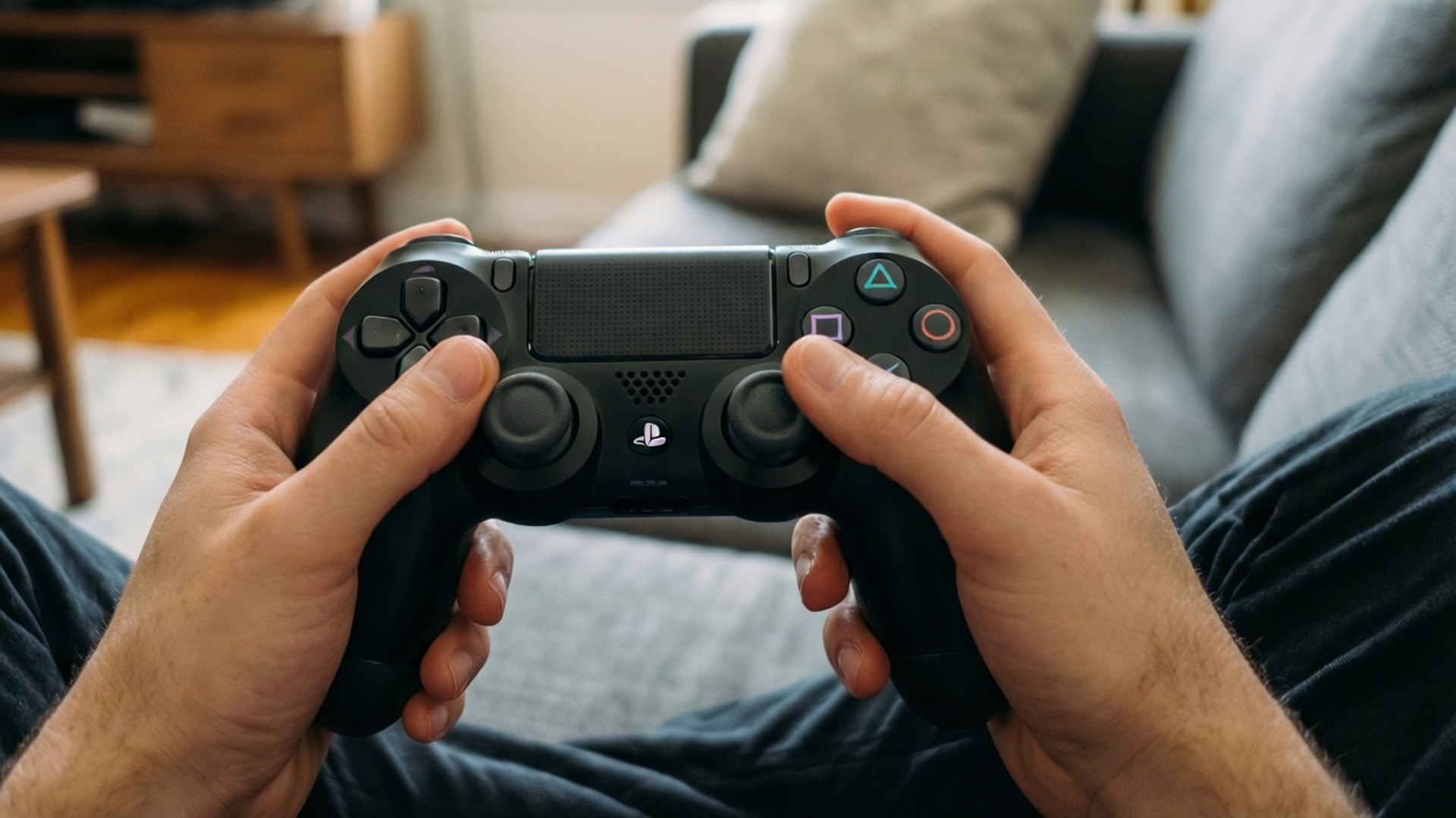 坐在梳化上手持 PlayStation 手掣的人