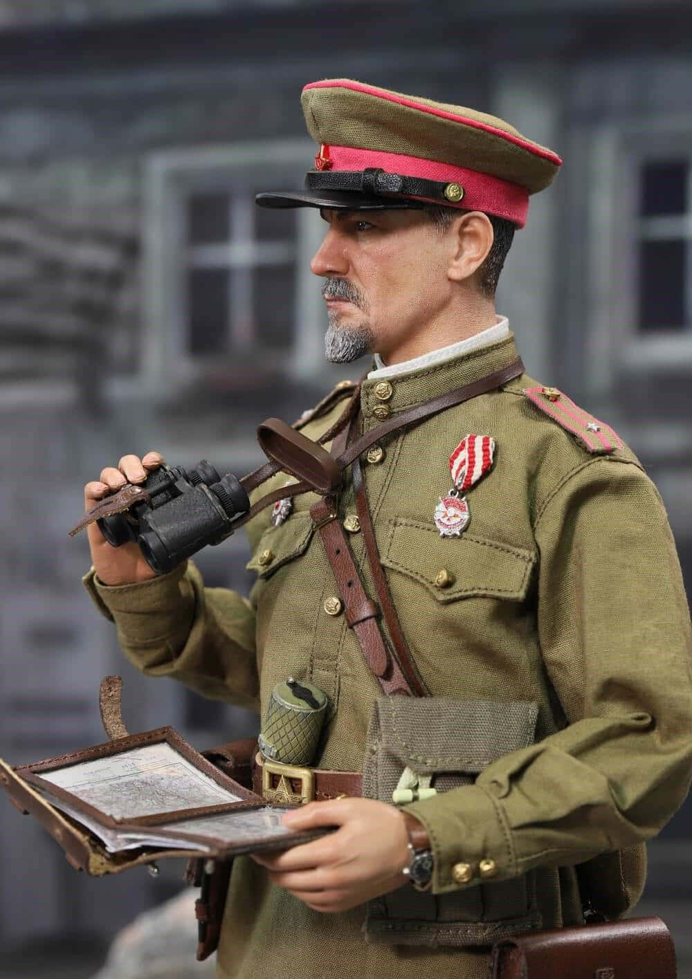  壁紙 — 一個鬍鬚士兵穿著橄欖色制服，手持望遠鏡和地圖，背景是模糊建築物的詳細人偶。