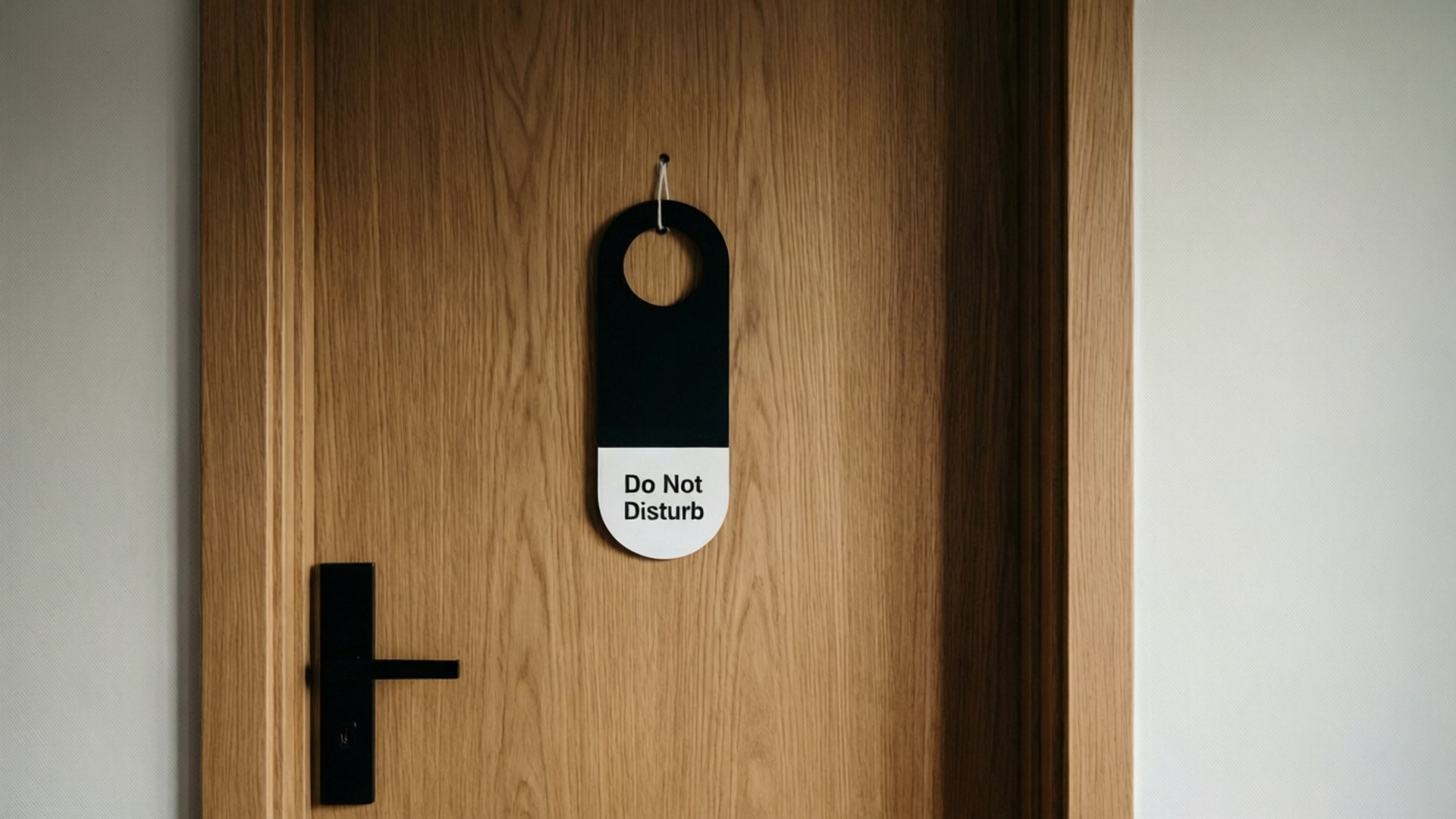 Do Not Disturb 桌布 壁紙 — 一個黑白嘅「請勿打擾」標誌掛喺淺色木門上，門有現代黑色手柄。