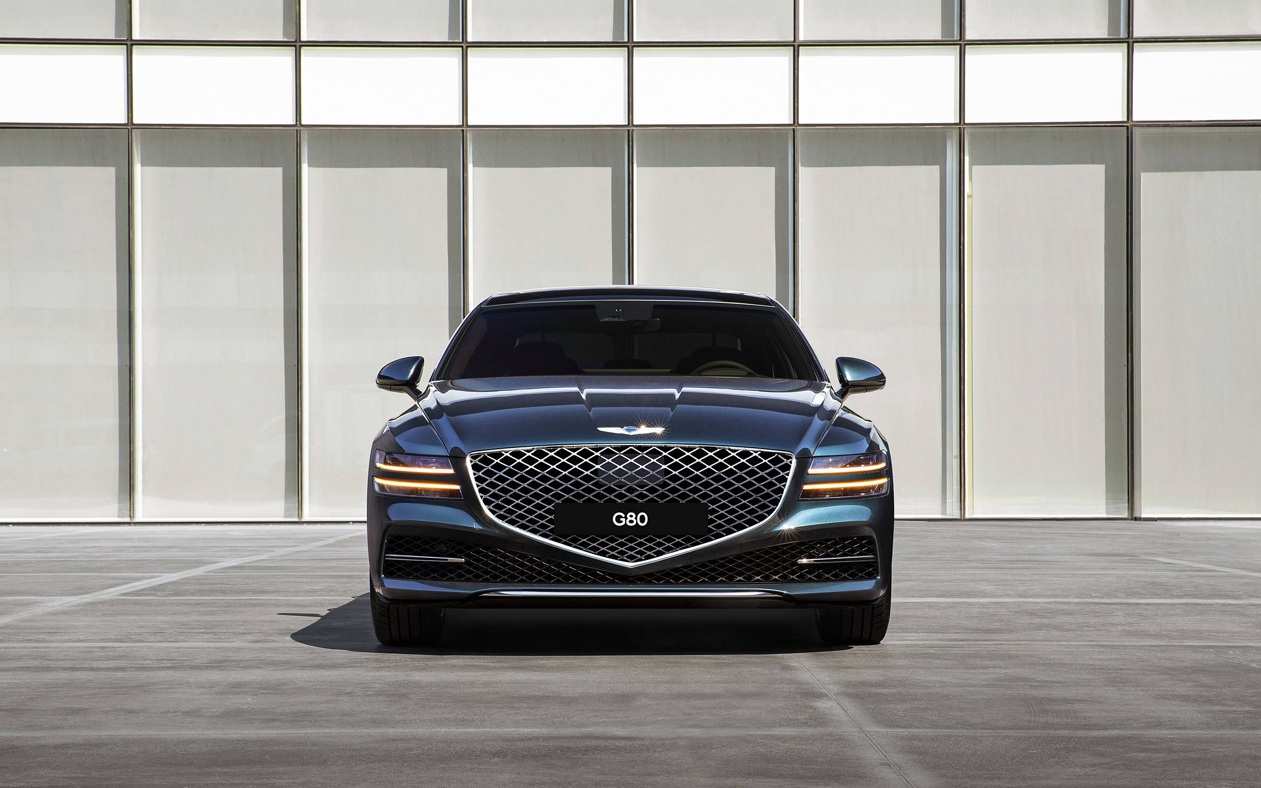 紅色豪華轎車：Genesis G80 壁紙 — 一輛時尚的深藍色 Genesis G80 豪華轎車面向現代玻璃和金屬建築外牆。