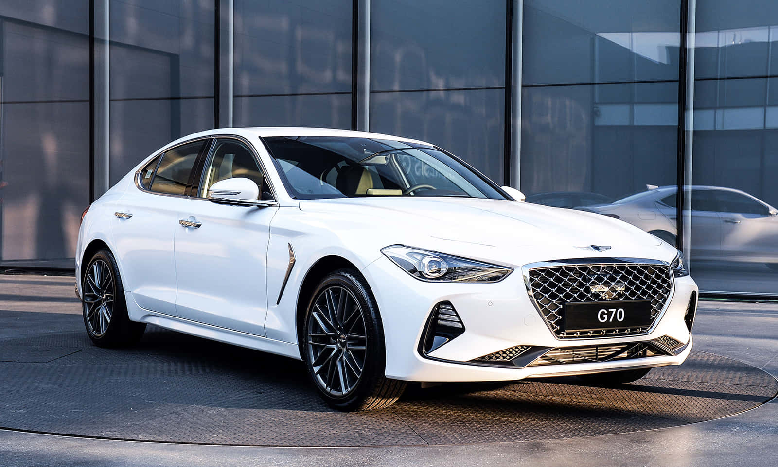 白色Genesis G70轎車停在玻璃建築前
