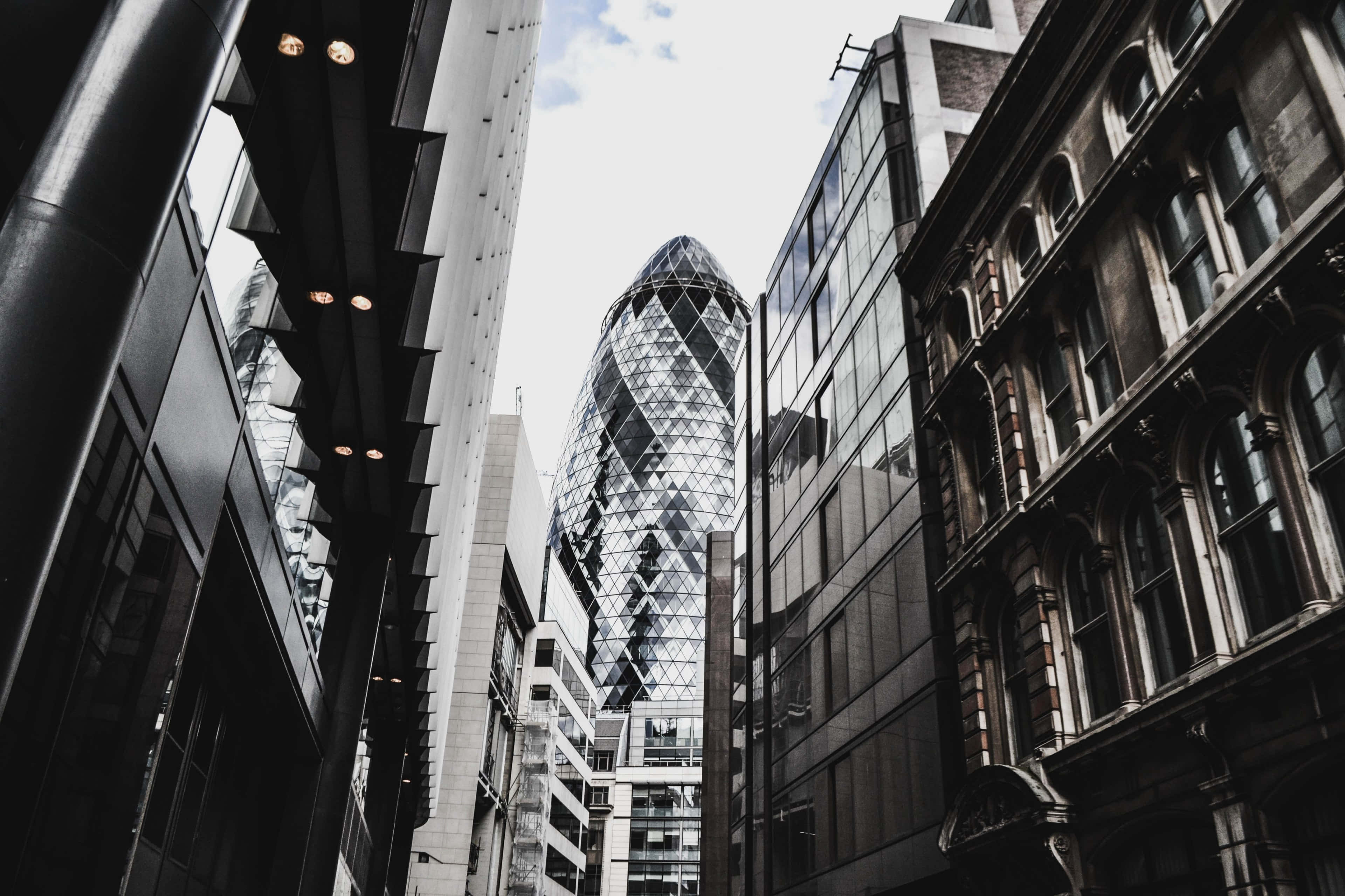 Gherkin 黑白現代風 壁紙 — 一張低角度黑白照片捕捉到標誌性的小黃瓜摩天大樓在倫敦歷史與現代建築之間聳立。