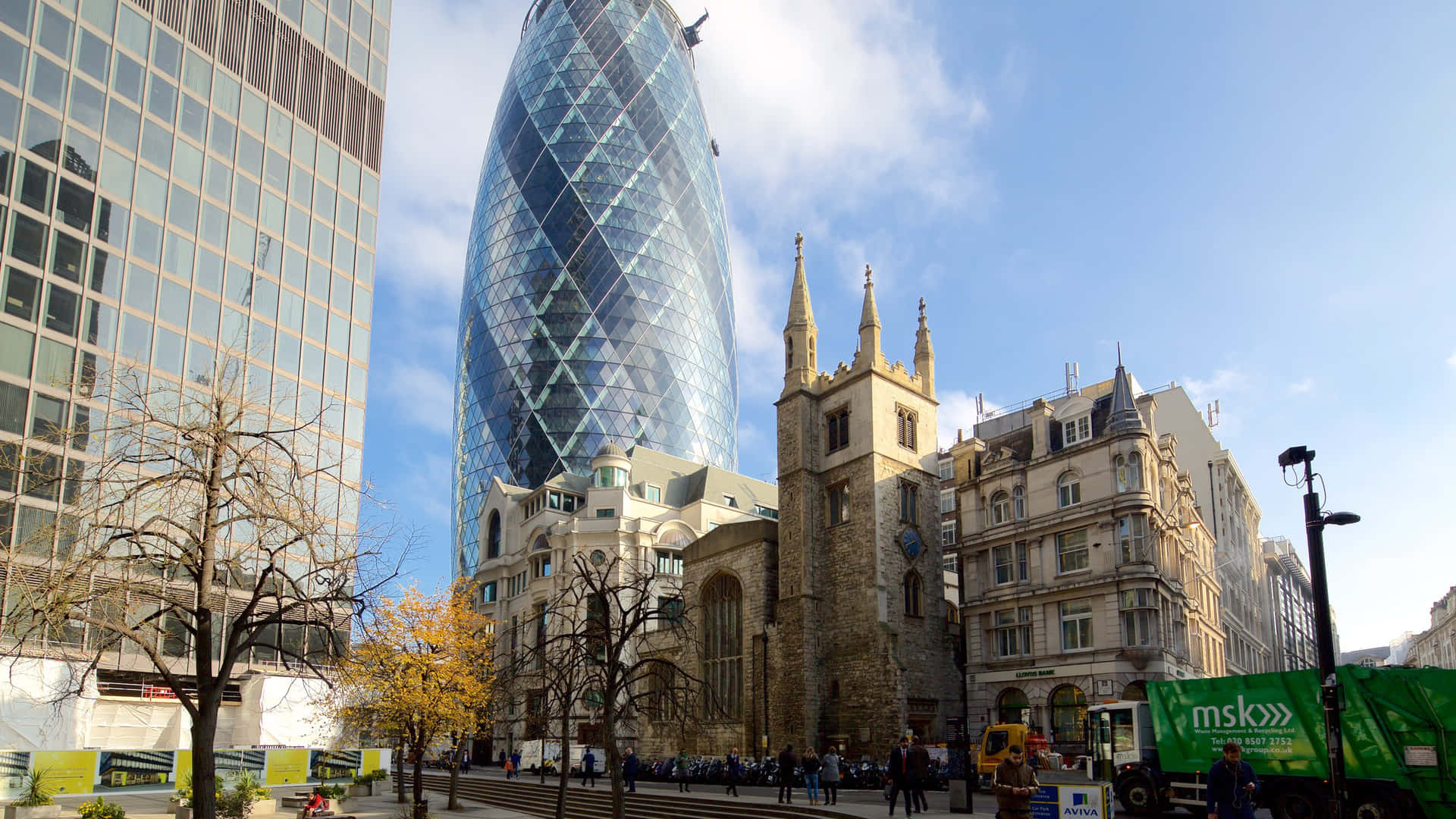 Gherkin 旁的舊建築 壁紙 — 現代玻璃摩天大樓在明亮藍天和零星白雲下，聳立於歷史石砌教堂之上。
