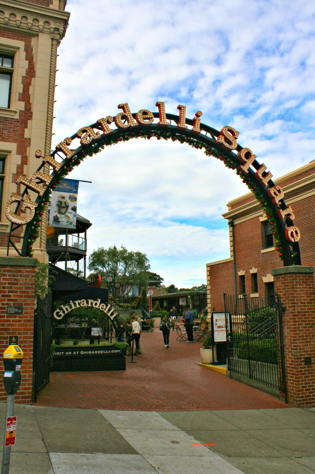 Ghirardelli Square入口，有磚拱門和行人在藍天下行走。