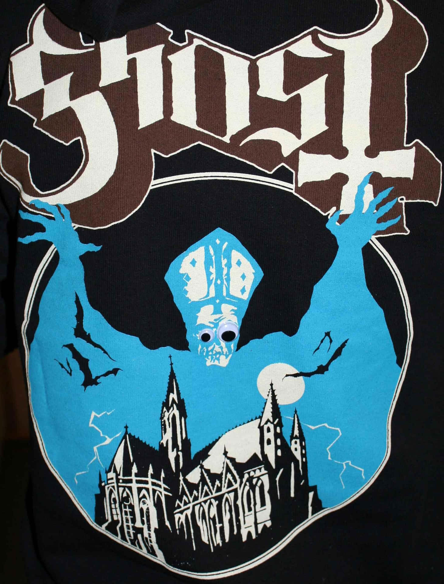 黑色T恤上的Ghost樂隊標誌，帶有藍色骷髏教宗和哥德式大教堂。