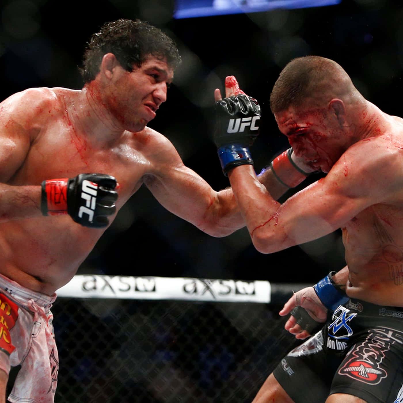 Gilbert Melendez擊敗Diego Sanchez獲首勝 壁紙 — 兩名血跡斑斑的MMA拳手在明亮的場館燈光下進行激烈的籠中對決。