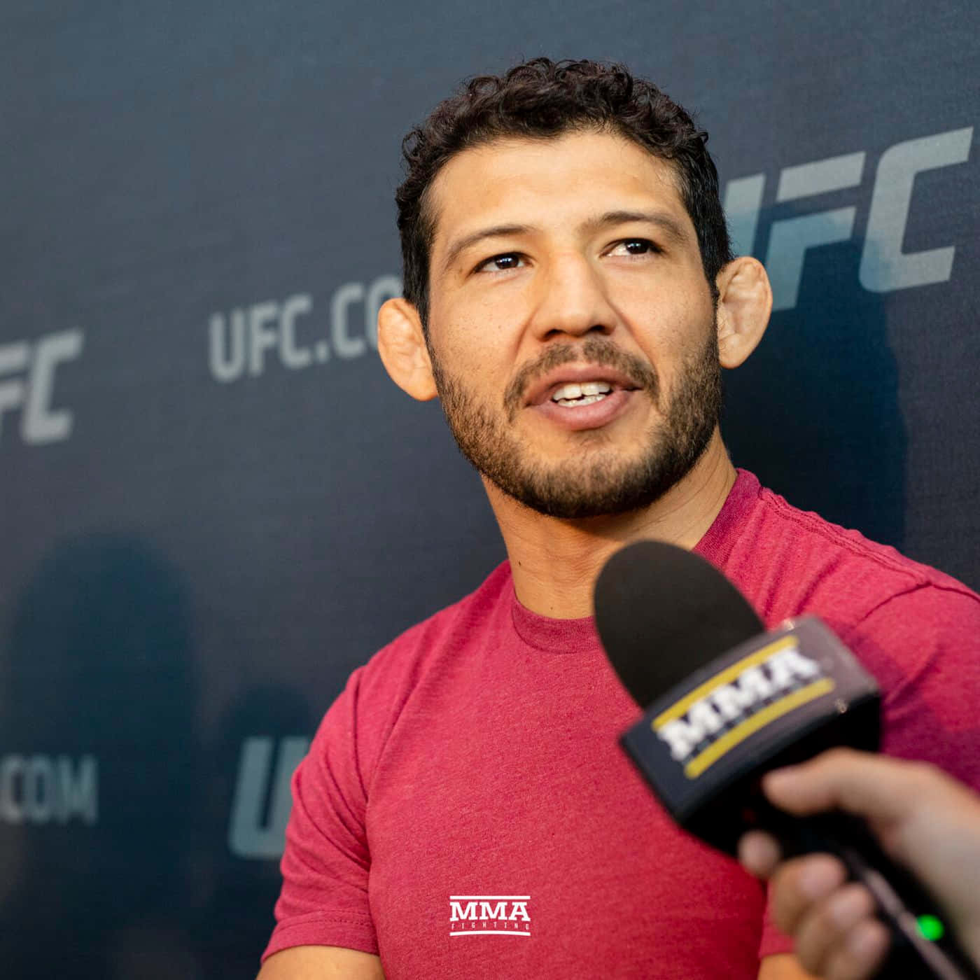 Gilbert Melendez接受UFC賽前專訪 壁紙 — 一位專注的混合武術家穿著紅色襯衫，在UFC新聞活動中對著MMA品牌麥克風講話。