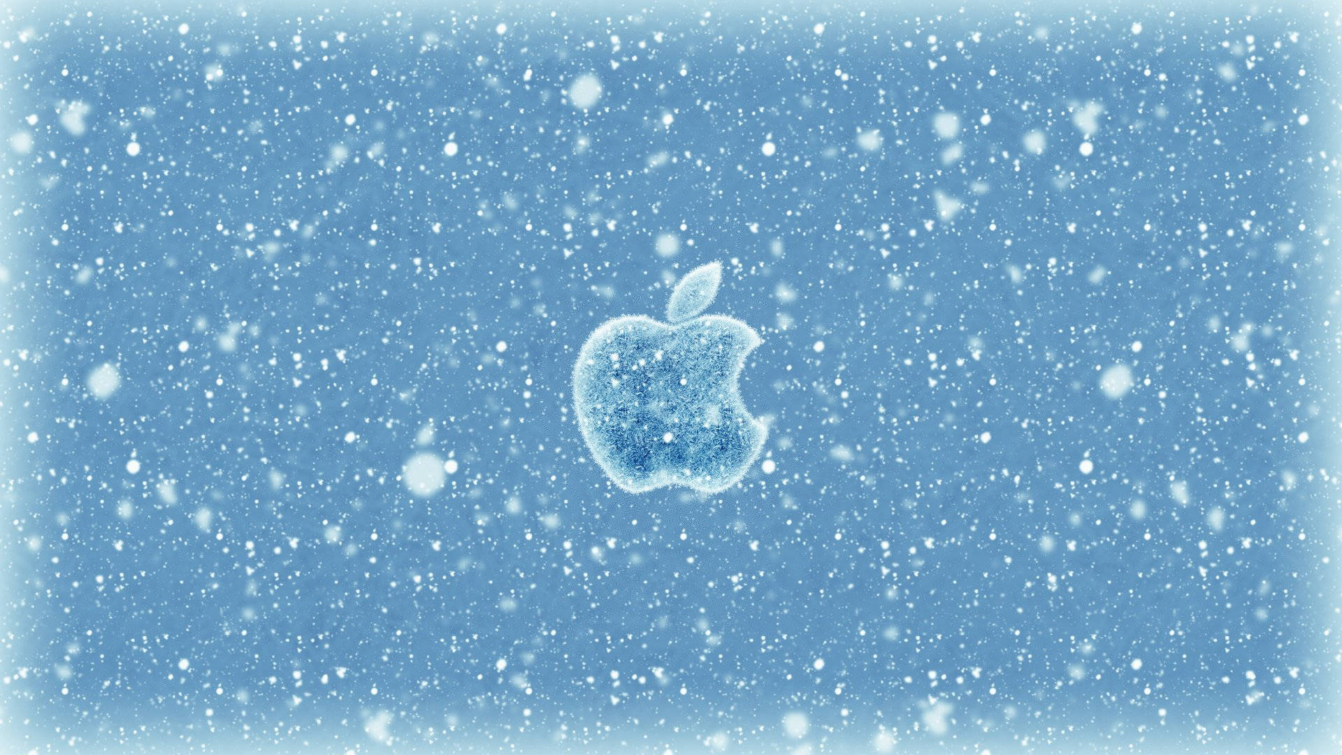 蘋果標誌雪中 壁紙 — 一個結霜的Apple標誌，置於柔和藍色漸變背景上的輕柔降雪中。