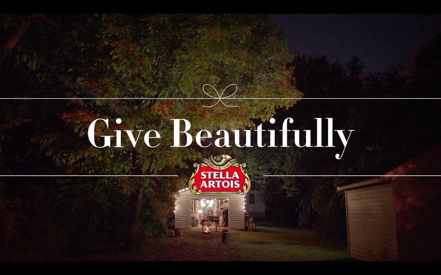 秋夜樹下木屋的夜景，帶有「Give Beautifully」和Stella Artois標誌。