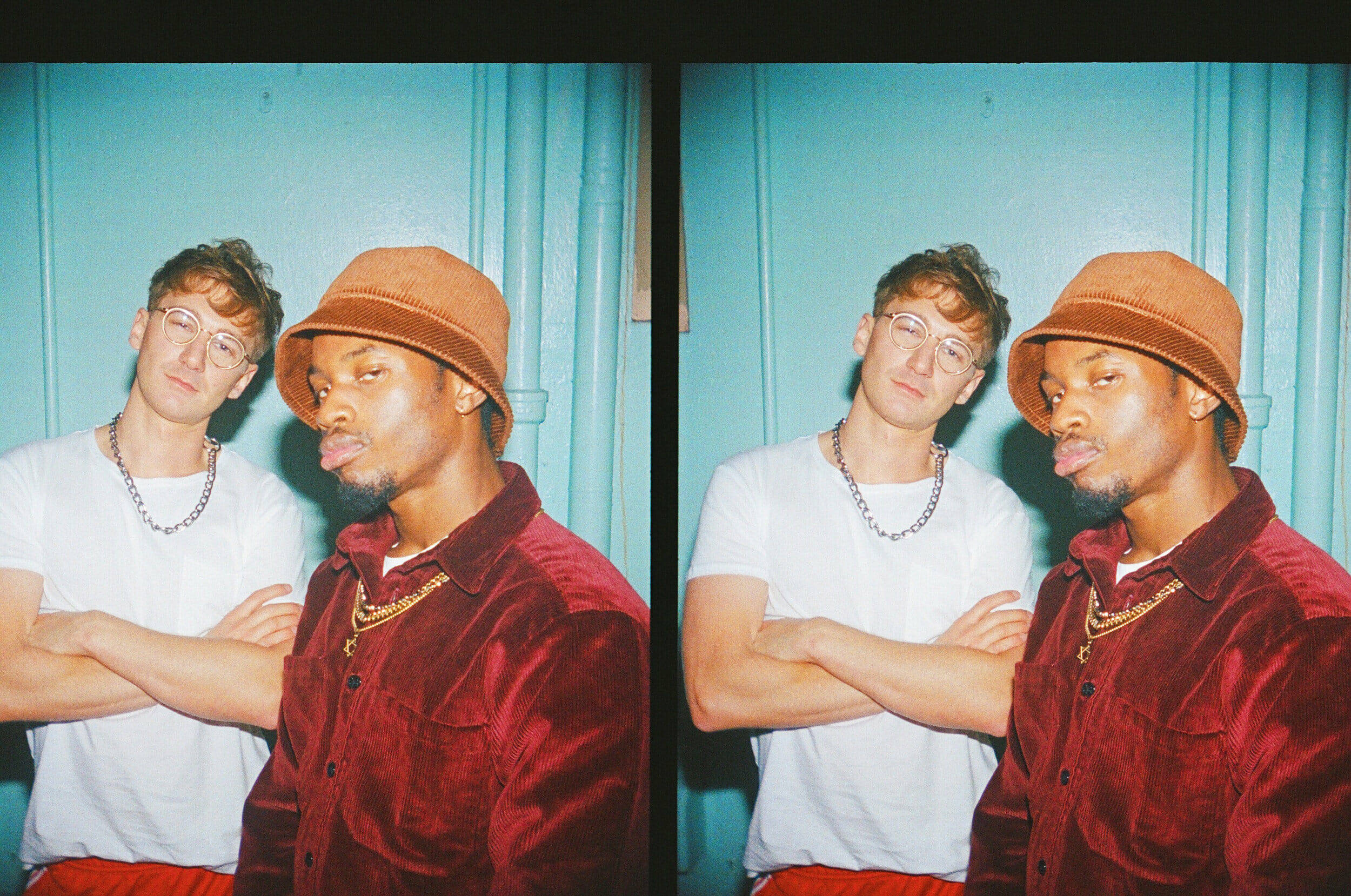 Glass Animals 經典復古風 Dave Bayley 壁紙 — 兩個男人在青綠色牆前擺出俏皮姿勢，一個伸出舌頭，另一個雙手交叉向後靠。