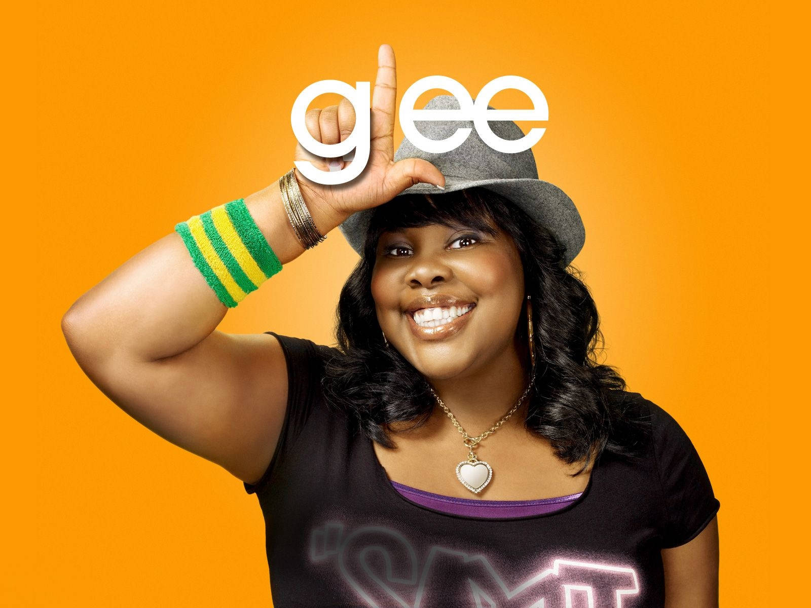 戴灰色帽子的女性在橙色背景上微笑，帶有「Glee」標誌