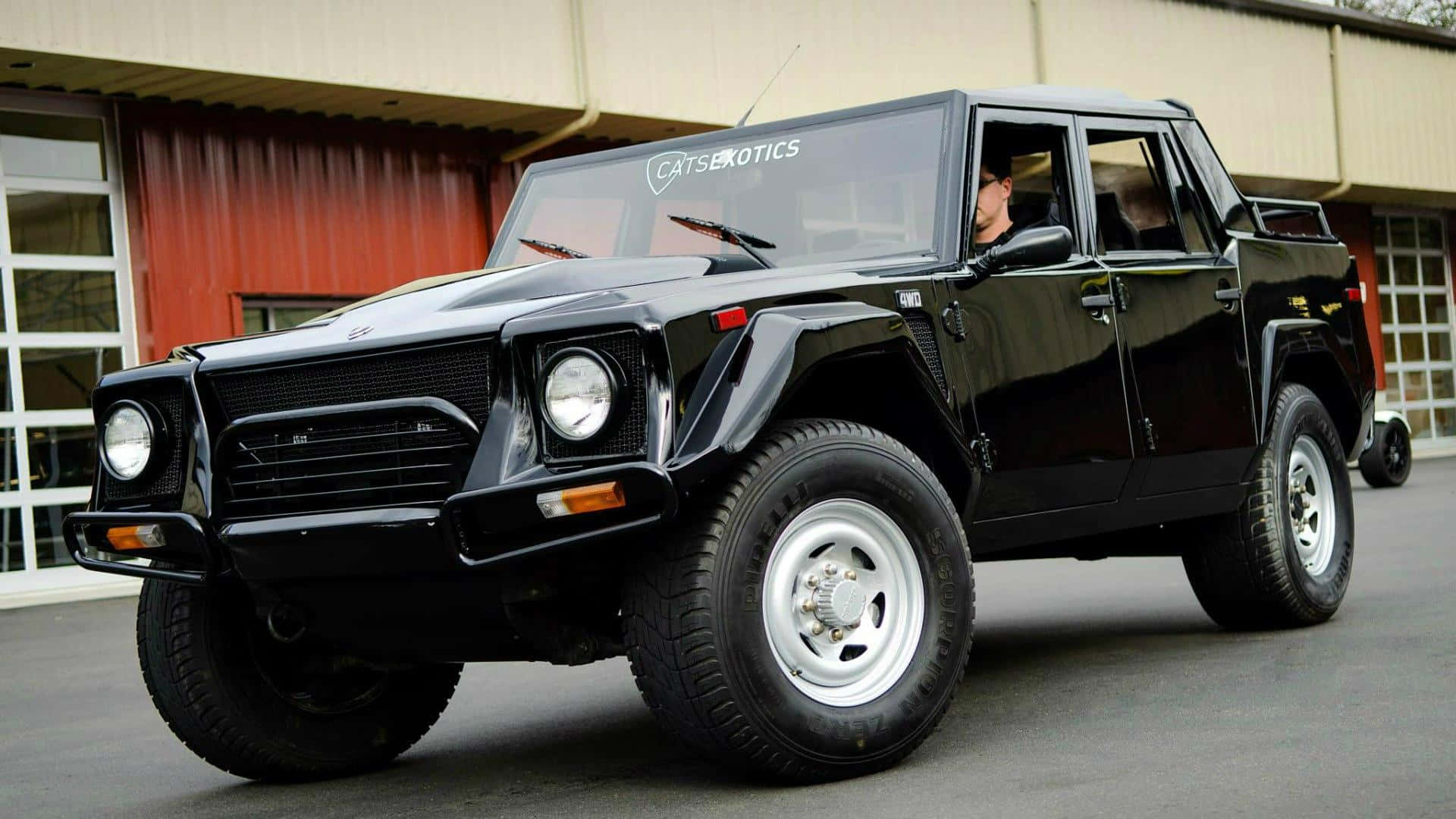 Lamborghini Lm002 桌布 壁紙 — 一架亮黑色林寶堅尼LM002豪華越野車停泊在車庫外，車內可見一人。