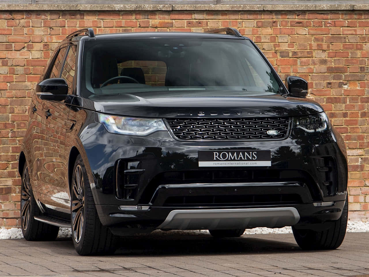 Land Rover Discovery 桌布 壁紙 — 一輛亮黑色Range Rover Sport停泊在紅磚牆前的鋪砌地面上。