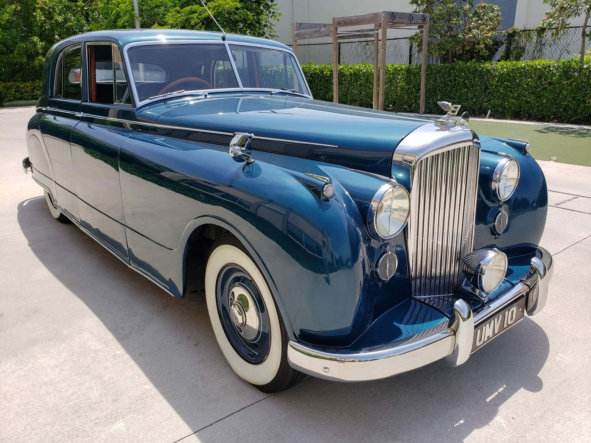 Bentley Mark Vi 桌布 壁紙 — 一輛光澤深藍色復古車，帶有鍍鉻裝飾和白色輪胎，停在陽光明媚的混凝土車道上。