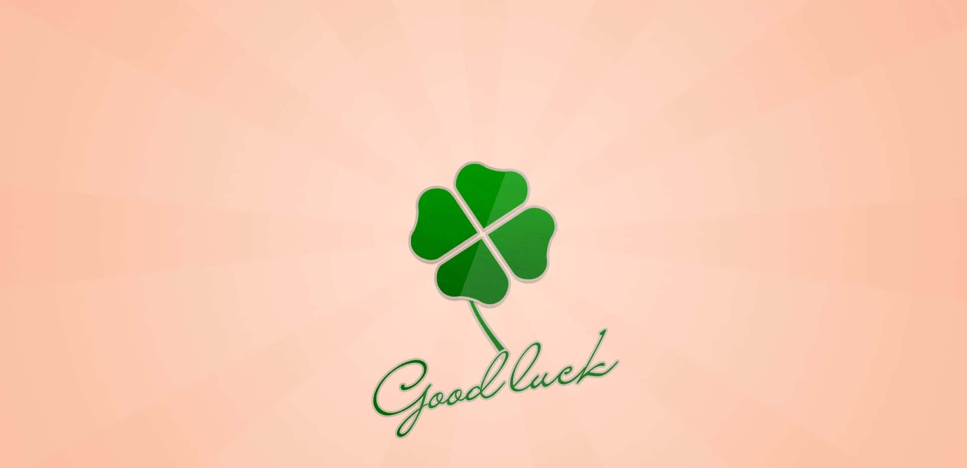  壁紙 — 一個帶有光澤的綠色四葉草，中央有 'Good luck' 字樣，背景為柔和蜜桃漸變色。