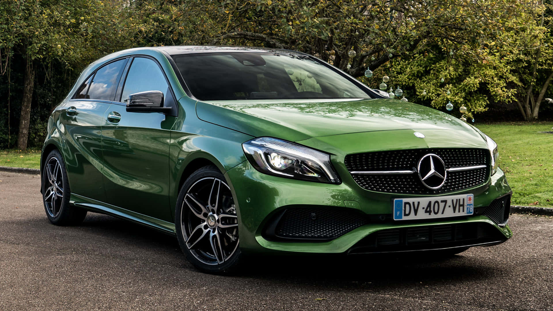 Mercedes Benz A-class 桌布 壁紙 — 一輛光澤的綠色平治A-Class掀背車停在鋪砌的道路上，背景有樹木和草地。