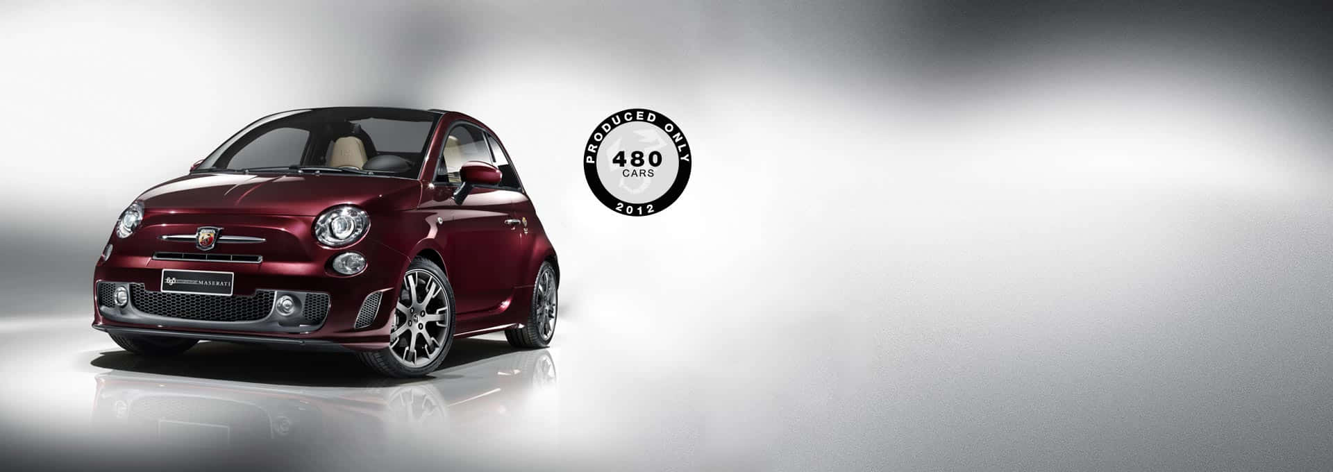 Fiat 500 桌布 壁紙 — 一輛光澤栗色的菲亞特500限量版汽車，2012年生產了480輛，在反射性工作室地板上以戲劇性燈光展示。
