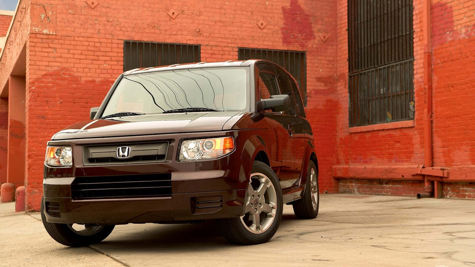 Honda Element 桌布 壁紙 — 一架亮面栗色本田Element SUV停喺一棟有鐵窗嘅風化紅磚建築前面。