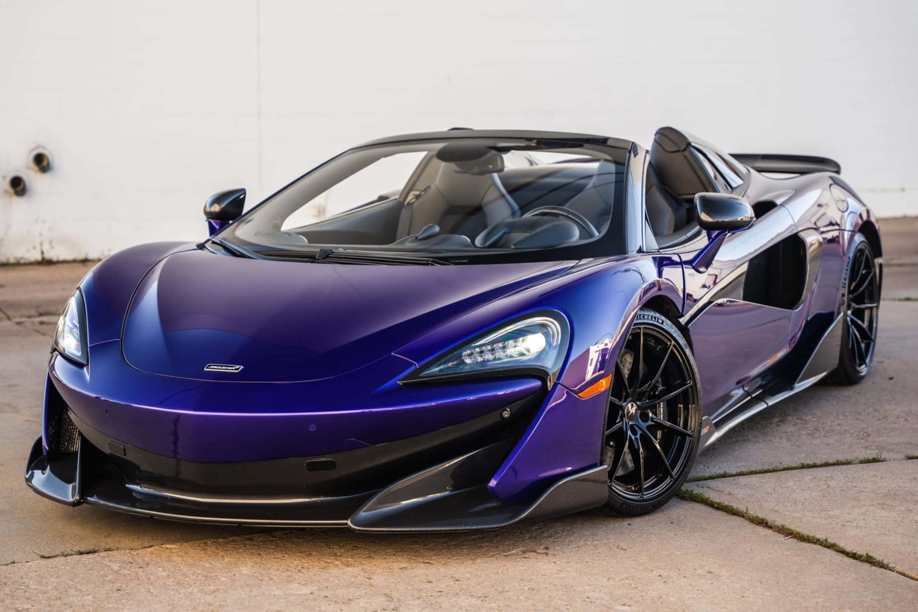 Mclaren 600lt Spider 桌布 壁紙 — 一架亮紫色McLaren 570S Spider開篷跑車停泊在混凝土上，後面是純白色牆壁。