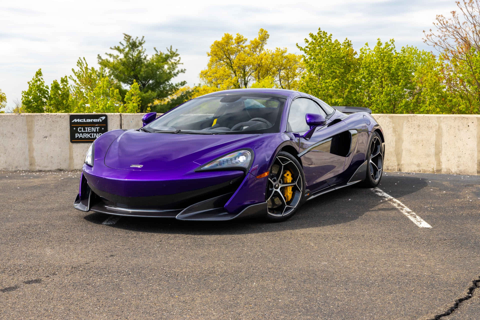 Mclaren 600lt Spider 桌布 壁紙 — 一輛光澤紫色McLaren跑車停泊在客戶停車場，背景有綠色樹木。