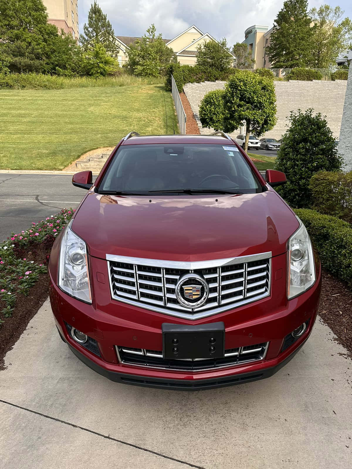 Cadillac Srx 桌布 壁紙 — 一輛亮紅色嘅Cadillac SRX喺混凝土車道上向前，背景係修剪整齊嘅綠色草坪同樹木。