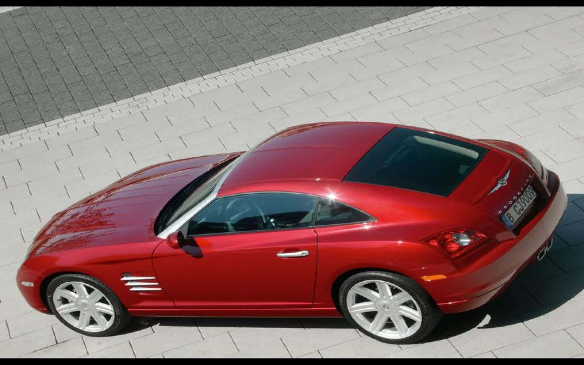 Chrysler Crossfire 桌布 壁紙 — 一輛光澤的紅色 Chrysler Crossfire 跑車停在淺灰色路面上，陽光普照。
