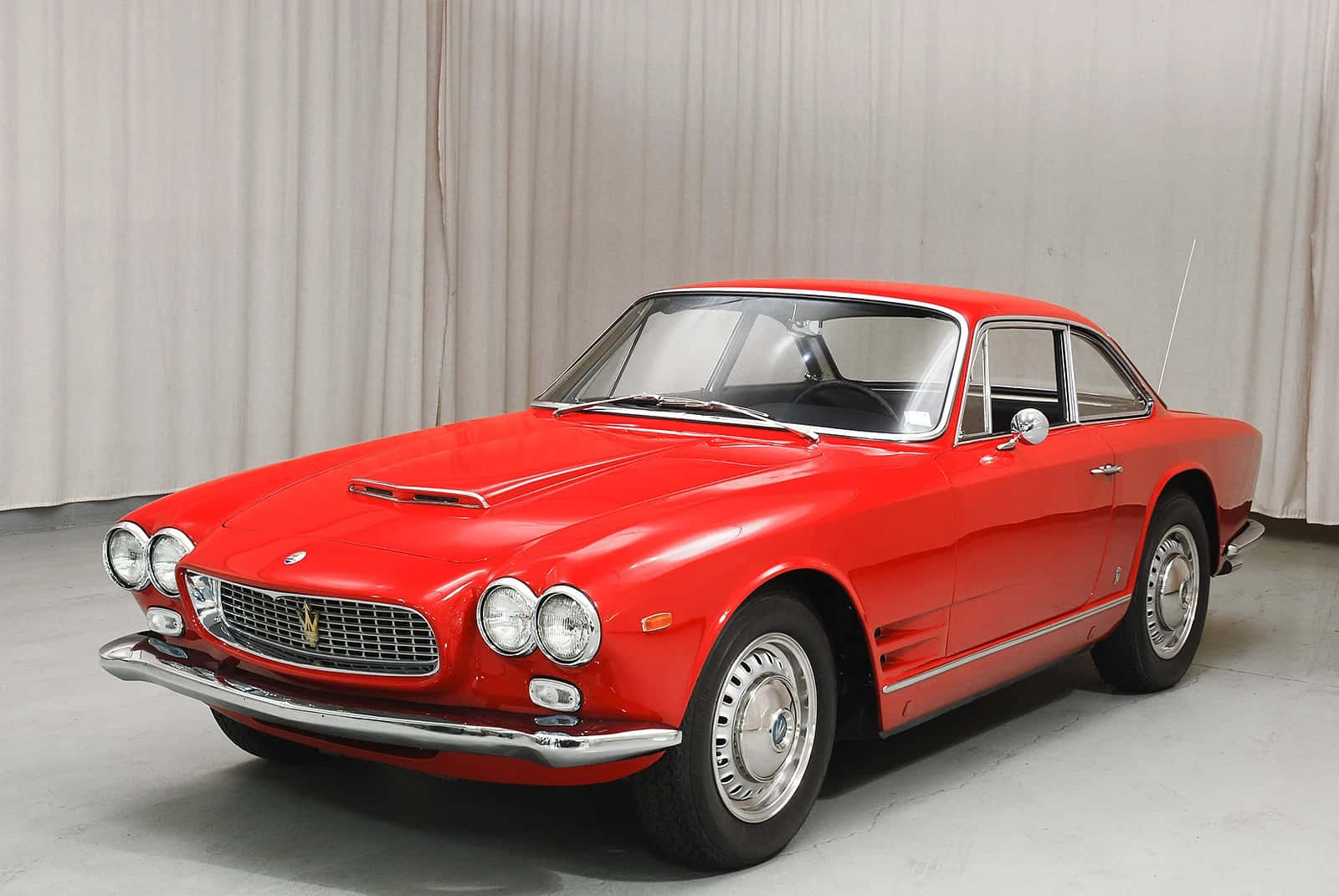  壁紙 — 一輛光澤紅色的經典法拉利250 GT Berlinetta，帶有鍍鉻裝飾和白色側壁輪胎，在垂簾背景前擺姿勢。