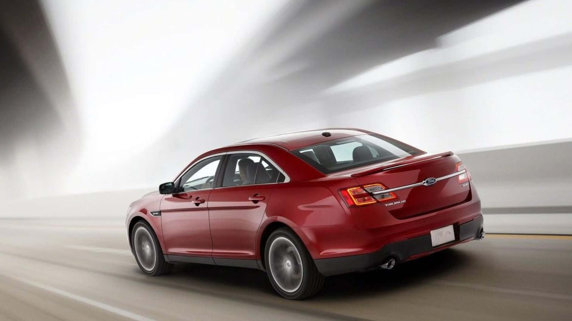 Ford Taurus 桌布 壁紙 — 一輛亮紅色福特 Taurus 房車在模糊的高速公路上向前疾馳，背景帶有動態條紋。
