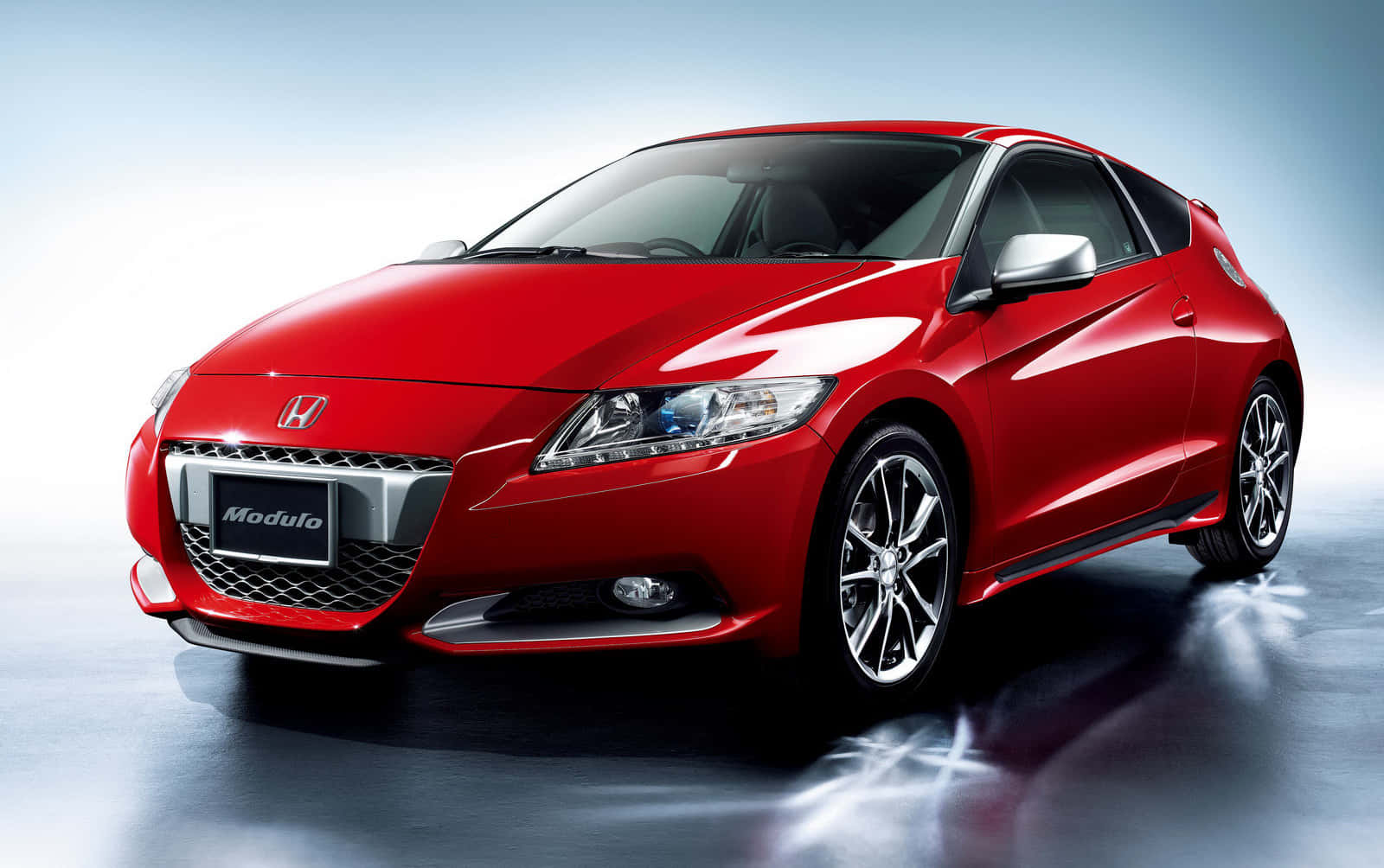 Honda Cr-z 桌布 壁紙 — 一輛光澤的紅色本田Modulo運動轎跑車在攝影棚燈光下於反光表面上閃耀。