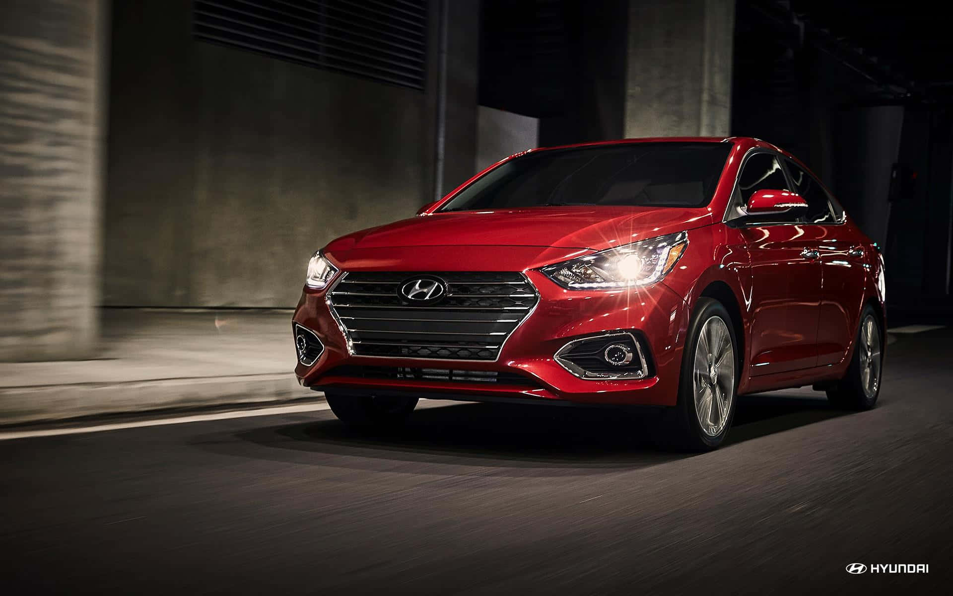 Hyundai Accent 桌布 壁紙 — 一輛亮紅色現代房車在昏暗的城市隧道中疾馳，瀝青路面上帶有動態模糊效果。