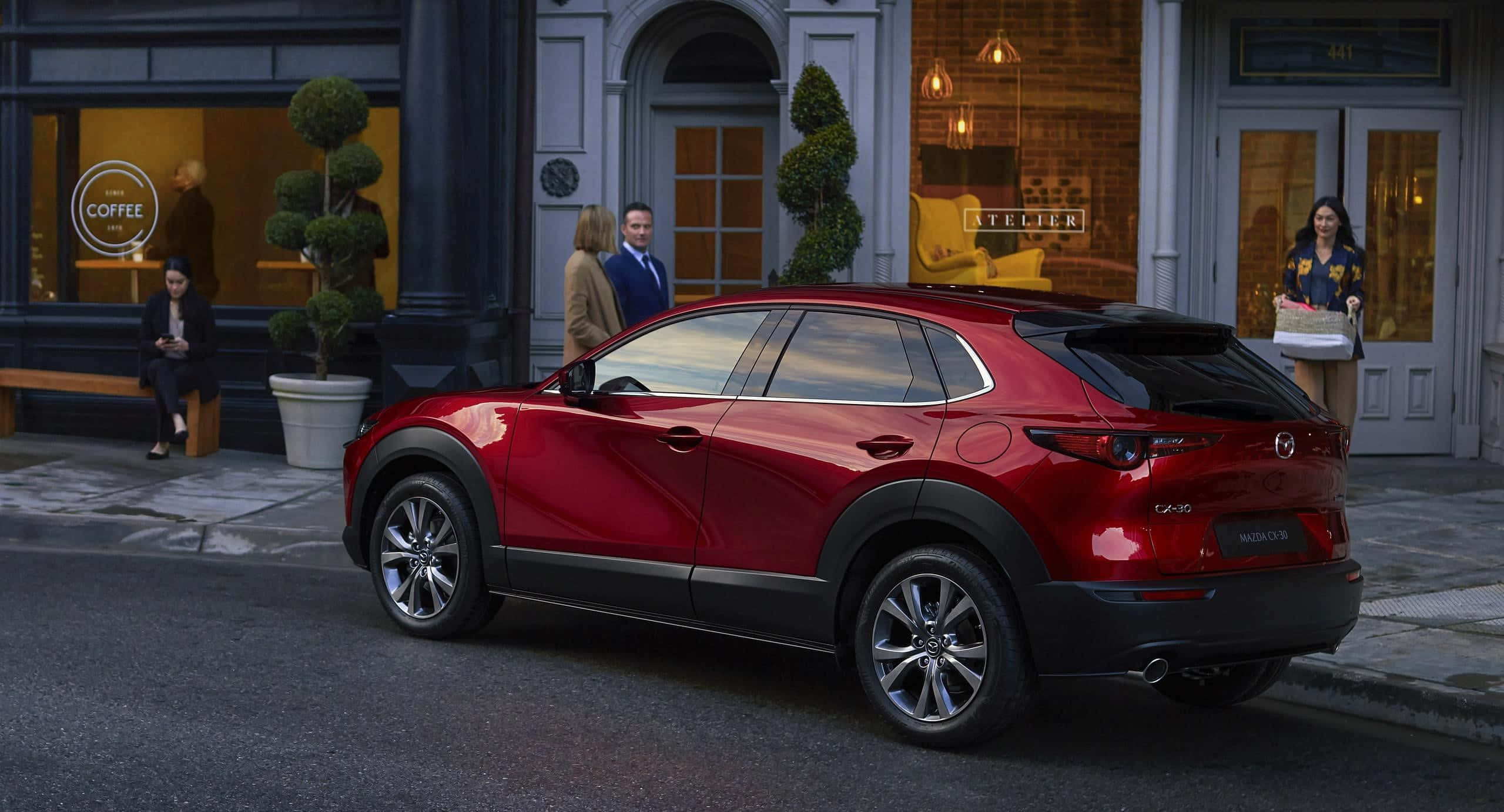 Mazda Cx-30 桌布 壁紙 — 一輛光澤的紅色Mazda CX-30 SUV停泊在城市的街道上，背景有行人和精品店舖面。