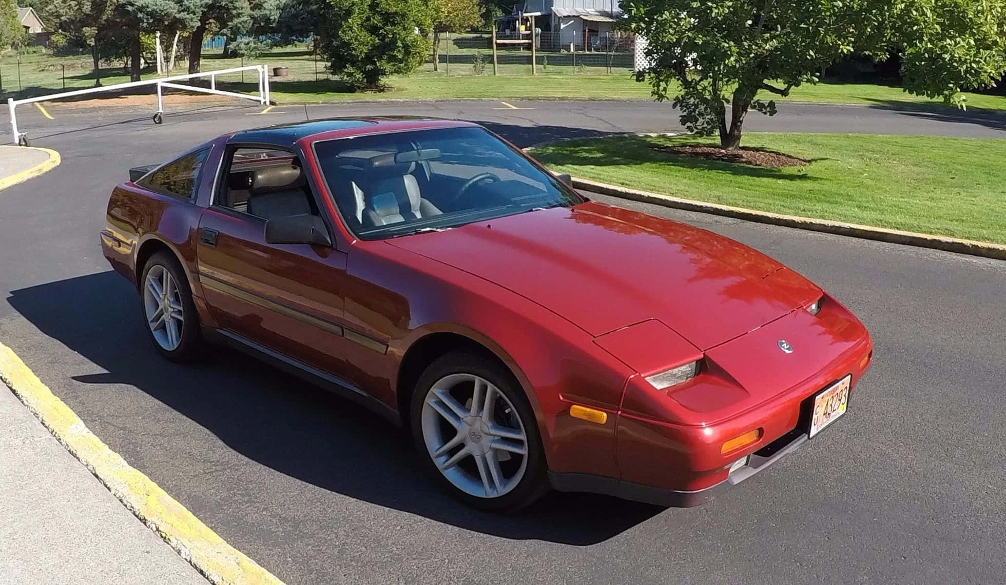Nissan 300zx 桌布 壁紙 — 一輛光澤的紅色跑車停泊在陽光明媚的郊區街道上，背景有綠色草坪和樹木。
