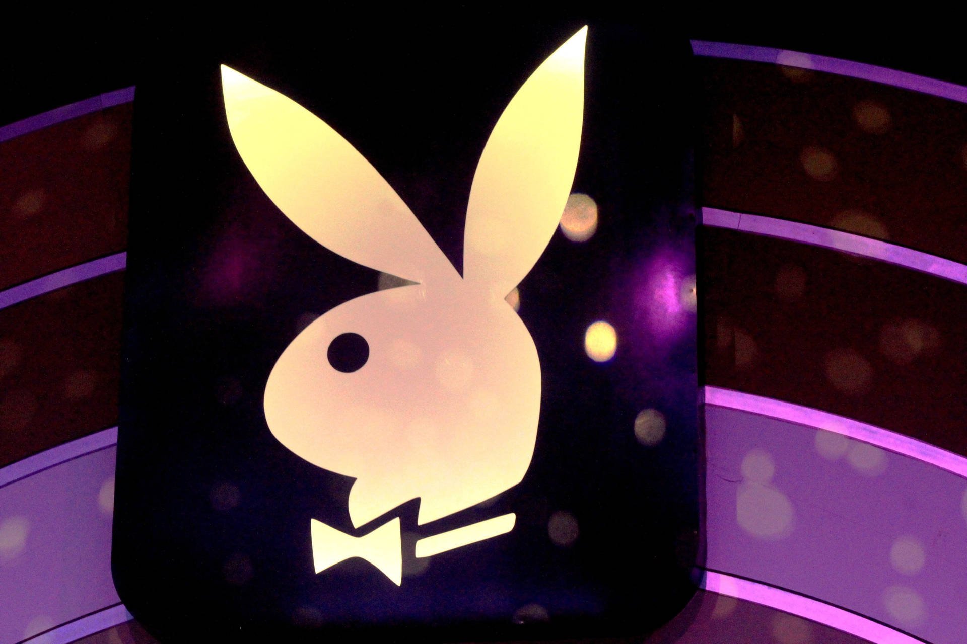 發光的Playboy兔子標誌配蝴蝶結，襯以紫色燈光。