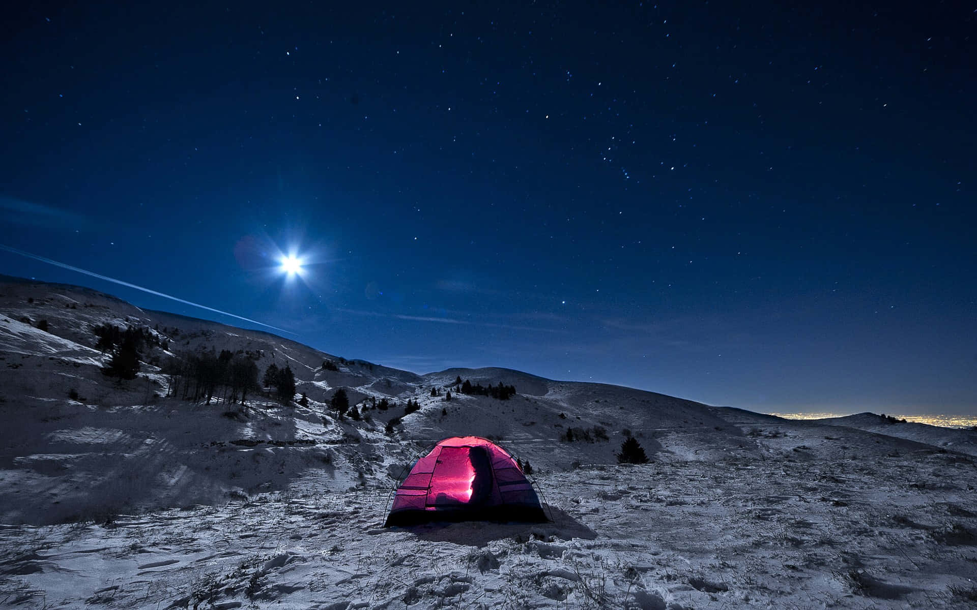 在星空夜空下，一個粉紅色帳篷在雪山景觀中溫暖地發光。