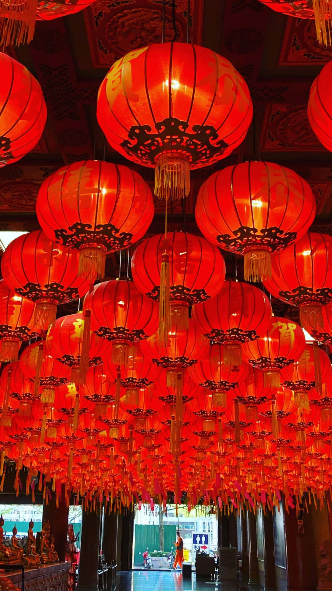  壁紙 — 一串串閃爍的紅色中式燈籠密集地懸掛在華麗的天花板上，為寺廟內部投下溫暖的光芒。