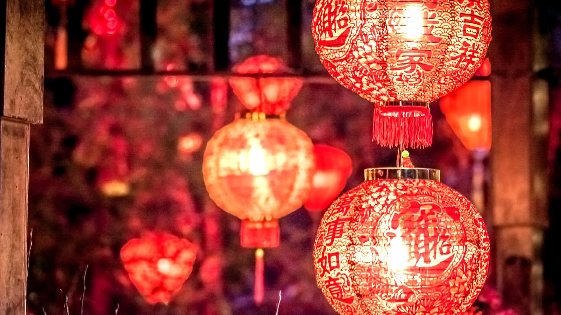  壁紙 — 發光的紅色中國燈籠，帶有精緻的鏤空和節日字符，溫暖地懸掛在模糊的夜晚背景下。