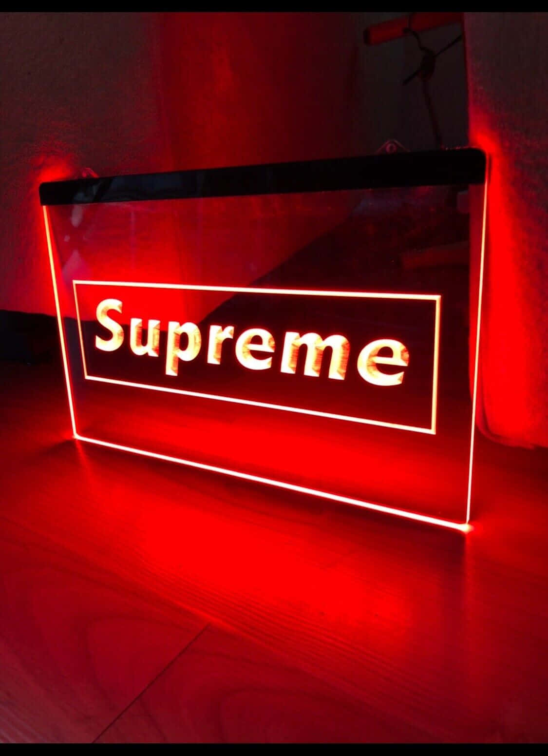 紅色霓虹燈Supreme標誌招牌在木地板上發光。
