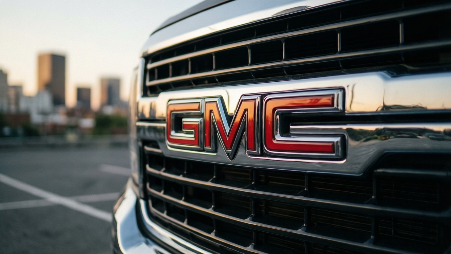 GMC 卡車格柵標誌在都市停車場反射日落。