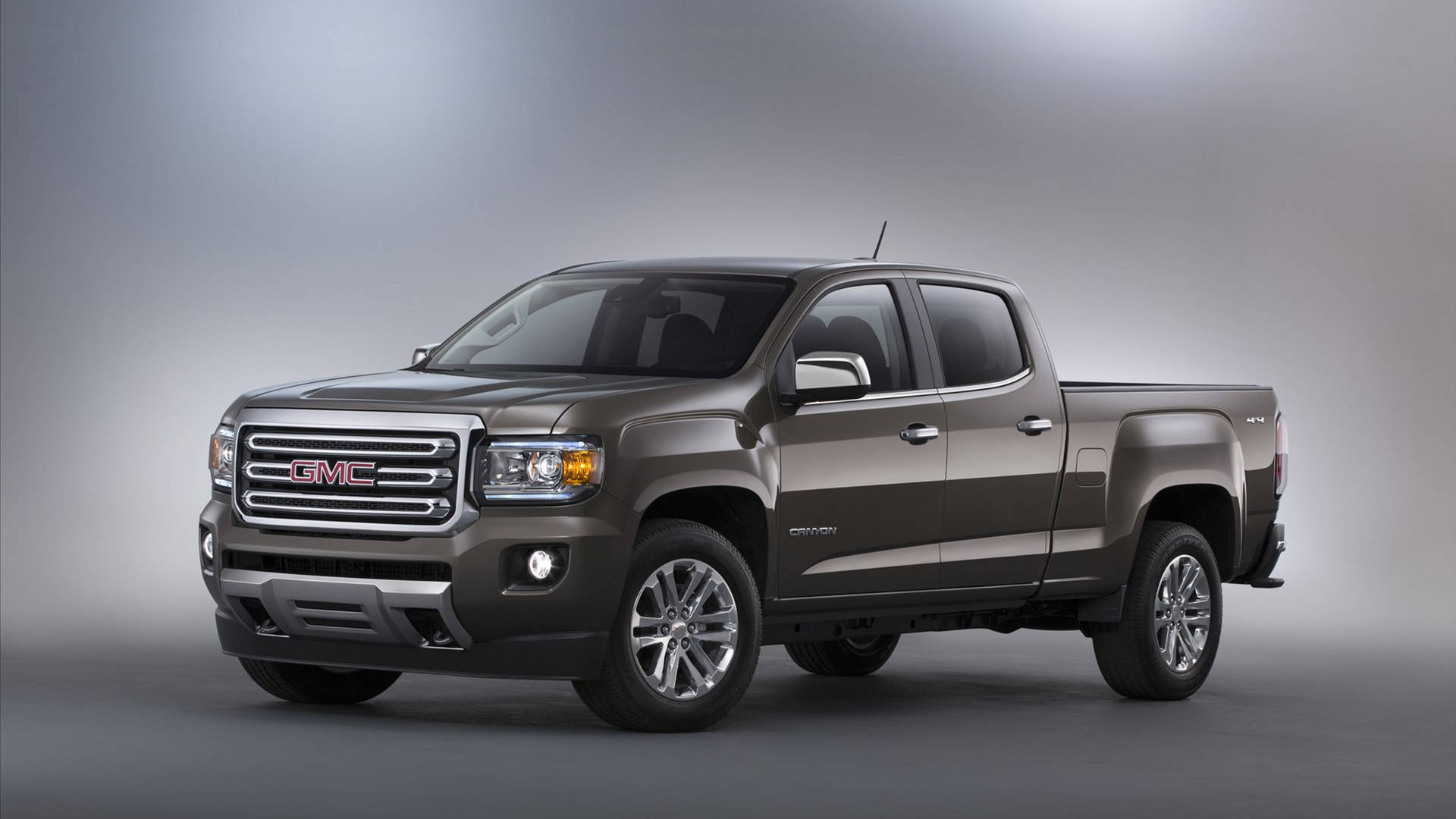 GMC 車輛於灰調環境中 壁紙 — 一輛時尚金屬棕色的GMC Canyon皮卡車在工作室中展示，配有柔和漸變燈光。