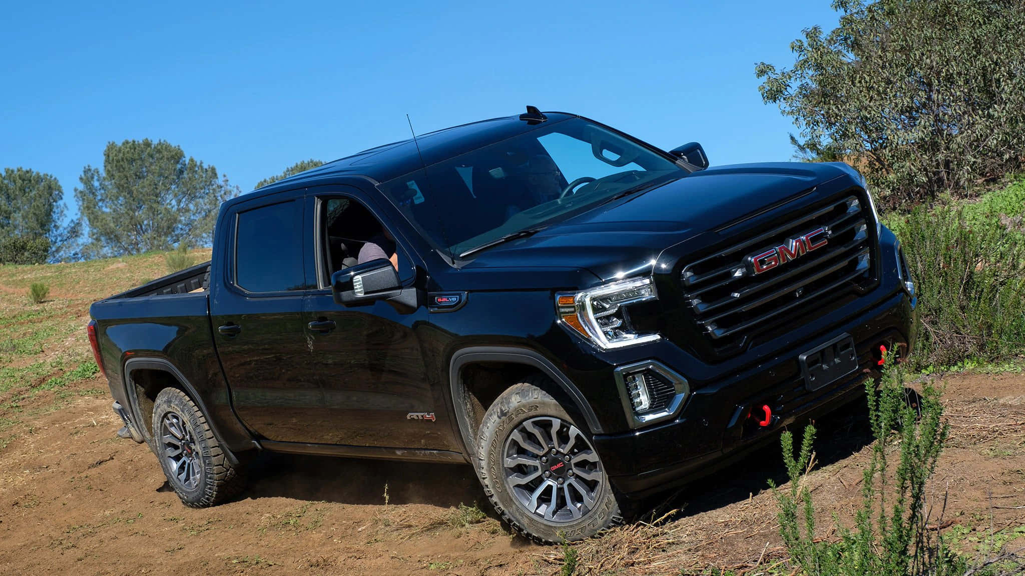 GMC全新豪華SUV——Terrain 壁紙 — 一架時尚的黑色GMC Sierra AT4 pickup truck停泊在泥路上，頭上是晴朗的藍天，附近有綠色灌木。