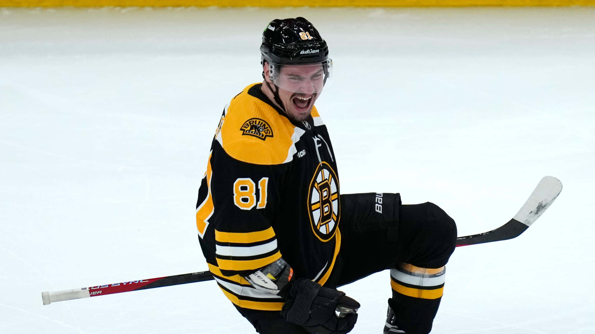 Go Bruins：慶祝冰上與場外的成就 壁紙 — 一名身穿黑黃色球衣的曲棍球運動員在冰上熱情地慶祝，手持球桿。
