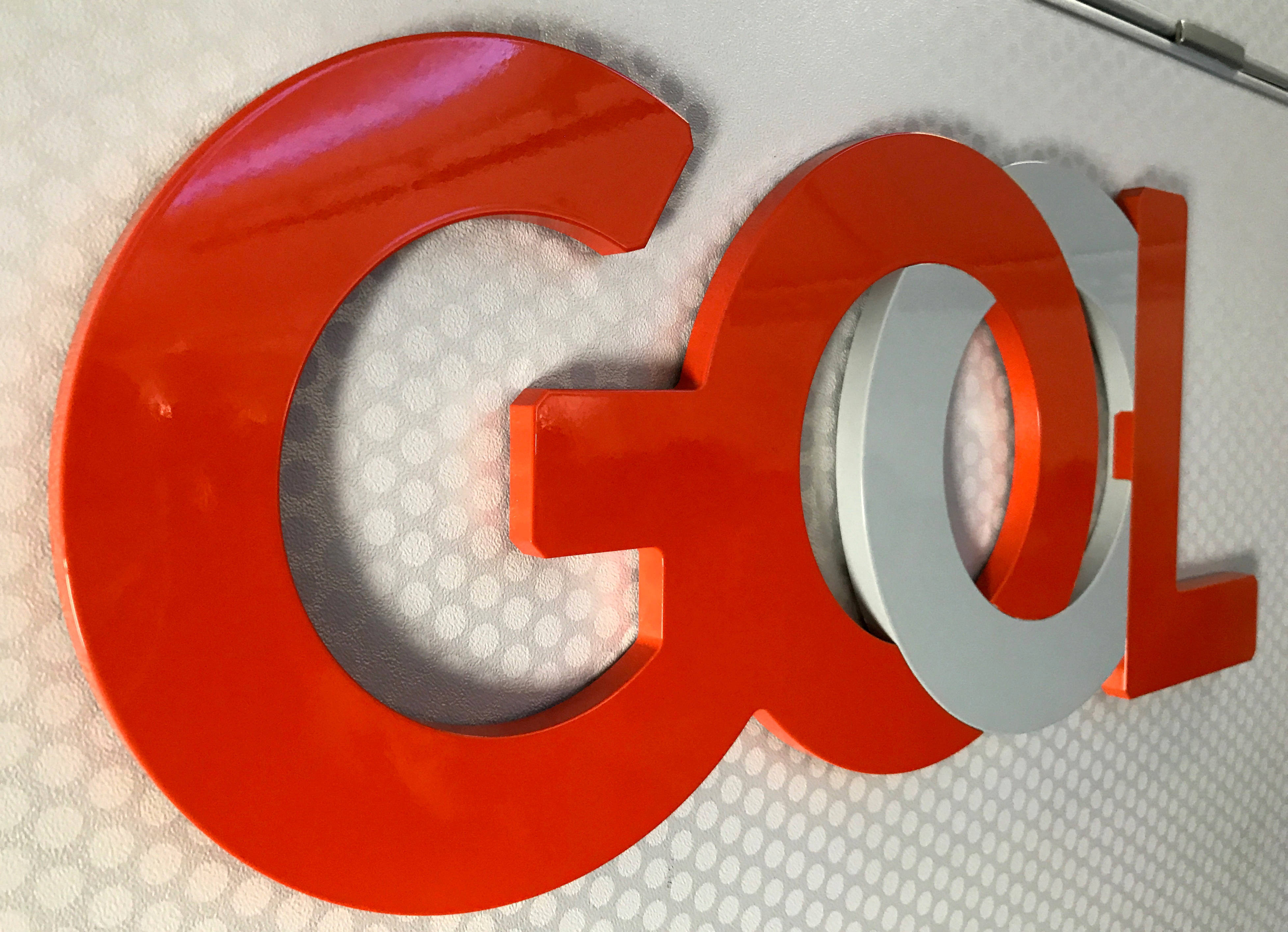 Gol 航空公司牆面標誌 壁紙 — 粗體紅色和銀色3D字母拼出GOL，安裝在帶有圓點圖案的紋理白色牆壁上。