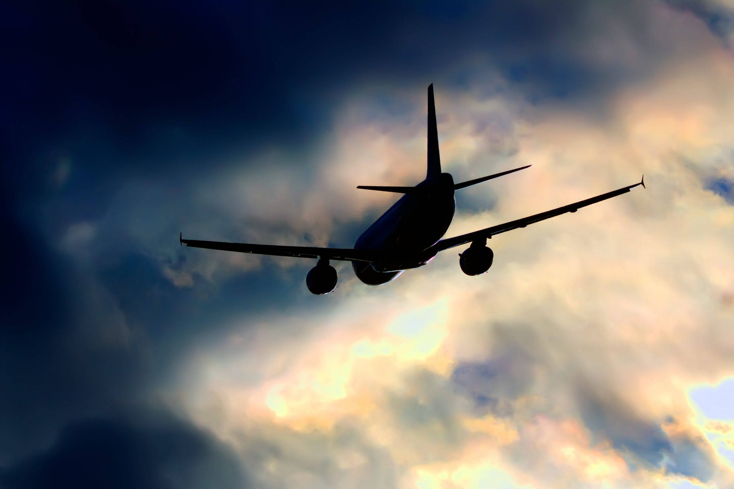 Gol 航空公司飛機剪影 壁紙 — 一架噴射機在金色雲朵和深藍色陰影的戲劇性天空下形成剪影。